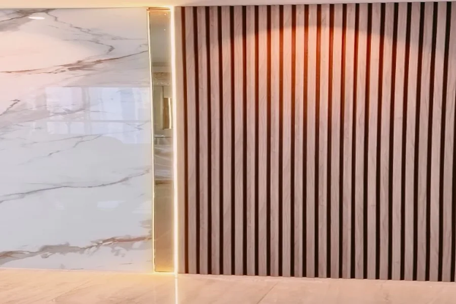 Close-up of a vertical acoustic slat panel next to a polished marble wall, with a lit doorway between them