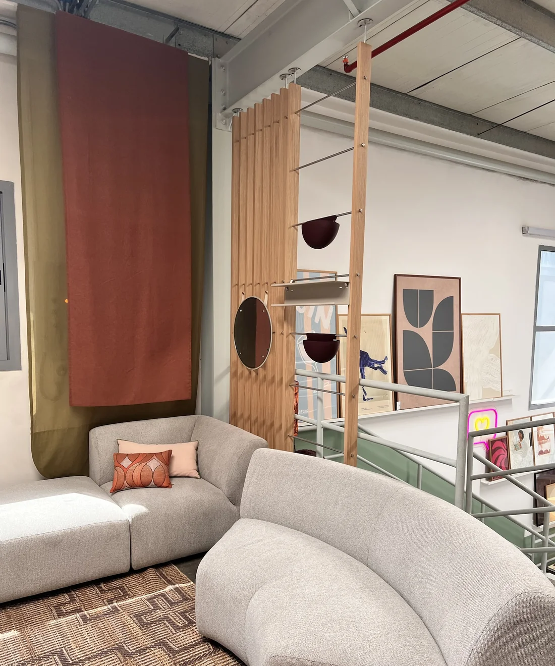 Lounge seating area with a WoodUpp Embrace slat room divider and hanging display shelves