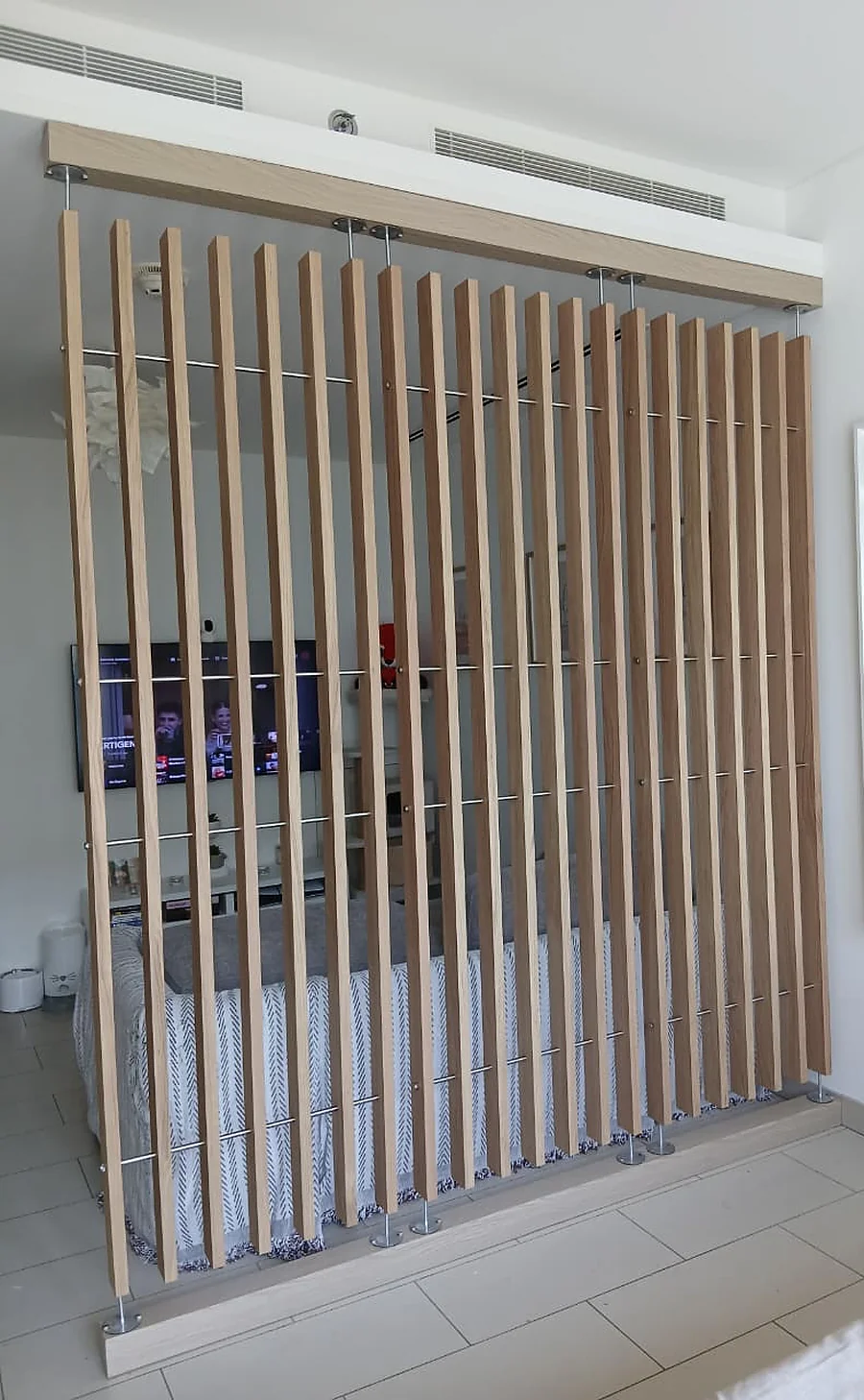 Before: a sheer curtain used as a room divider between the living area and the bed in a studio apartment
